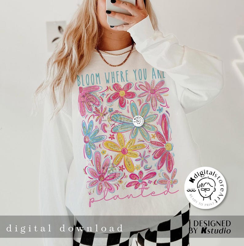 May include: White sweatshirt with a colourful floral design and the text "Bloom Where You Are Planted".