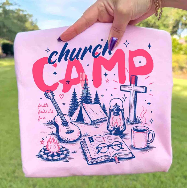 K&ouml;nnte beinhalten: Ein hellrosa Sweatshirt mit einem grafischen Design mit den Worten "church CAMP" in Rosa und Blau. Das Design umfasst eine Gitarre, ein Zelt, eine Laterne, ein Kreuz, ein Lagerfeuer, ein Buch und eine Kaffeetasse. Die Worte "faith friends fun" sind ebenfalls enthalten.