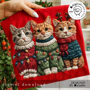 May include: A red fabric featuring an embroidered design of three cats wearing festive sweaters and Christmas lights. The cats have detailed fur and are adorned with holiday accessories. Text at the bottom reads "digital download" and "designed by Kstudio."