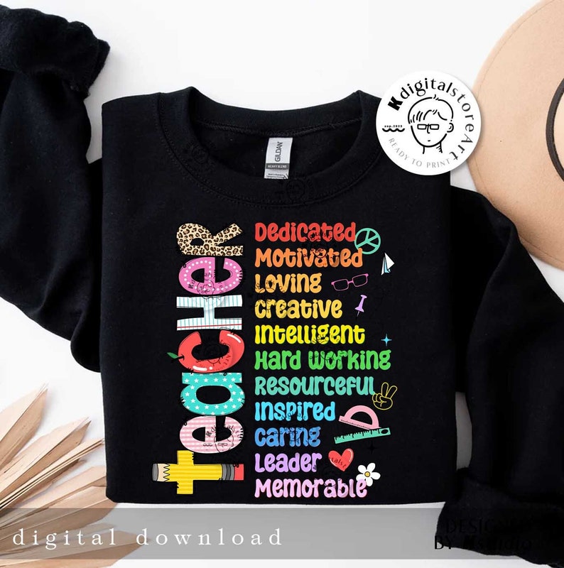 May include: Black sweatshirt with a rainbow-colored word art design that spells out "teacher" with positive adjectives describing the profession. The design includes a red apple, a pencil, a peace sign, a ruler, a heart, and a flower.