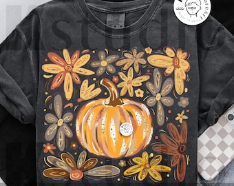 May include: Dark gray t-shirt featuring a pumpkin and floral design in shades of orange, yellow, and brown. The words "digital download" are printed at the bottom. A round logo with text is on the upper right.