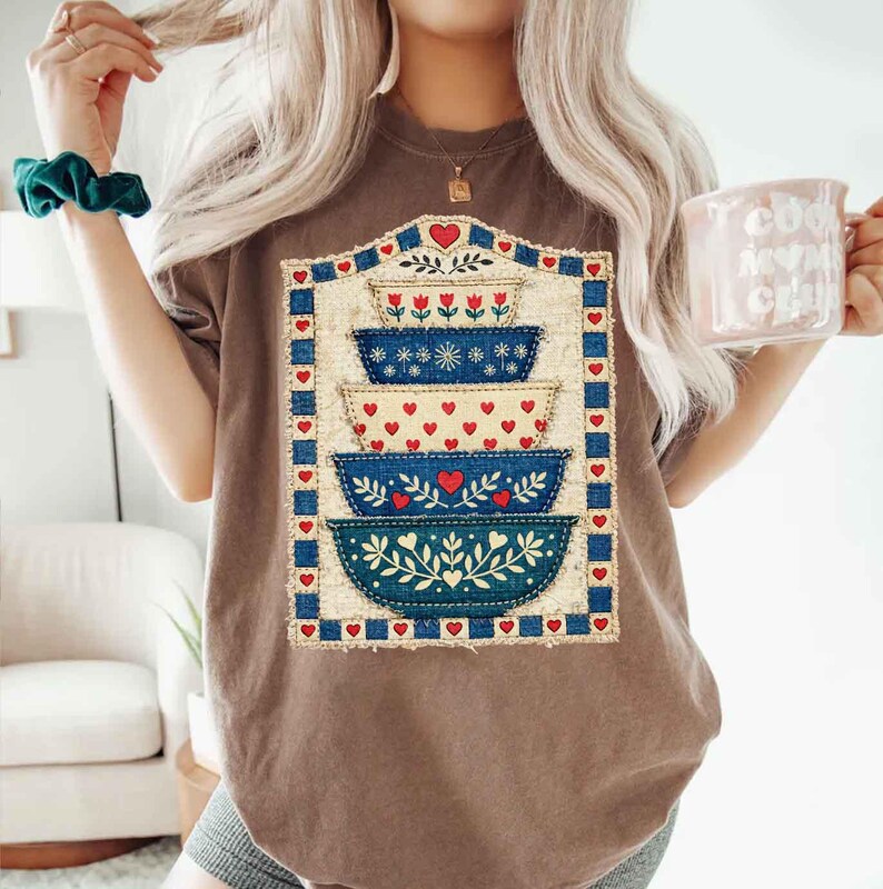 Pu&ograve; includere: T-shirt marrone con un design a ciotole impilate con cuori rossi e motivi floreali blu. Il design &egrave; incorniciato da un bordo blu e accenti di cuori rossi. La maglietta &egrave; in stile casual.