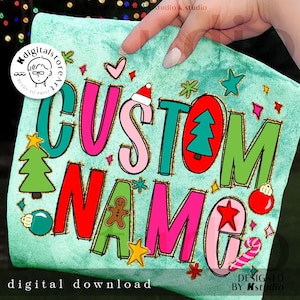 Puede incluir: Un cojín turquesa con las palabras "CUSTOM NAME" en letras coloridas y festivas. El diseño incluye ilustraciones navideñas como un árbol de Navidad, adornos y un bastón de caramelo. Las palabras "digital download" están en la parte inferior.