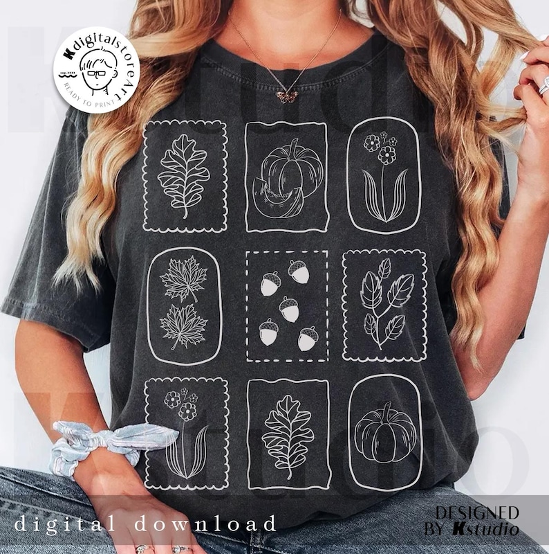 May include: Dark gray t-shirt featuring nine white line drawings of fall-themed elements, including leaves, pumpkins, acorns, and flowers, within decorative frames. The words "digital download" are at the bottom. The design is by Kstudio.