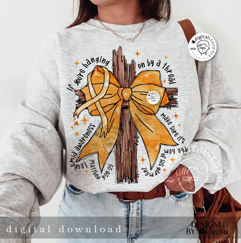 May include: A grey sweatshirt with a yellow ribbon tied around a brown wooden cross. The text "If you're hanging on by a thread make sure it's the hem of His garment" is printed on the sweatshirt.  The text "Leukemia Awareness Matthew 9:20-22" is also printed on the sweatshirt.