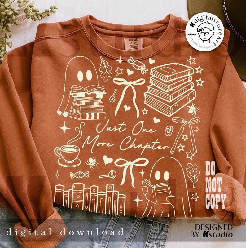 May include: A rust-colored sweatshirt with a white graphic design featuring books, ghosts, bows, and the text "Just One More Chapter." The design includes stars, a coffee cup, and the words "digital download" and "do not copy."