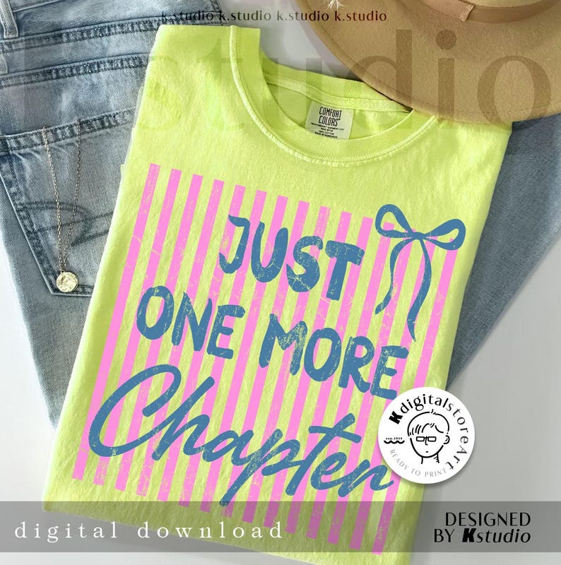 Puede incluir: Una camiseta verde ne&oacute;n con el texto azul "JUST ONE MORE Chapter" sobre rayas verticales rosas. La camiseta est&aacute; doblada sobre unos vaqueros azules, con un collar dorado y un sombrero beige.