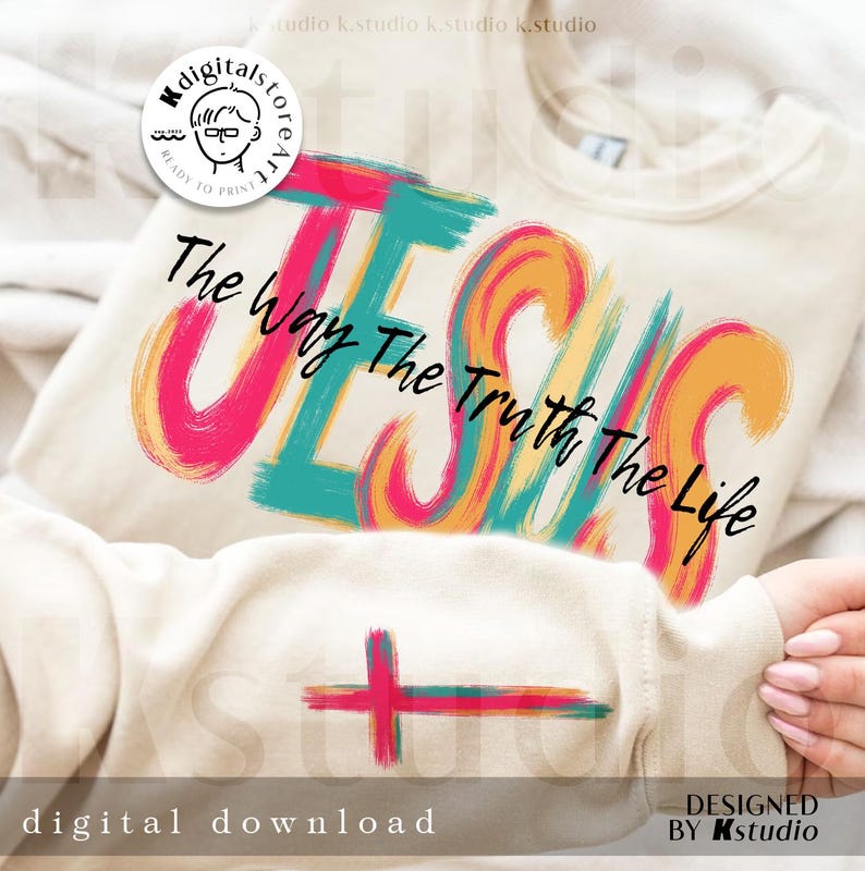 May include: Cream-colored sweatshirt with the word "JESUS" in large, colorful brushstrokes. The text "The Way The Truth The Life" is above and below the word. A cross design is on the lower part of the shirt. The words "digital download" and "designed by Kstudio" are at the bottom.