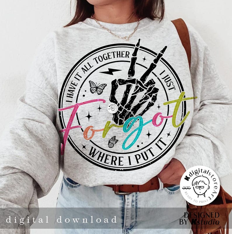 May include: A gray sweatshirt with a black and white graphic print of a skeleton hand making a peace sign. The graphic is surrounded by a circle with the text "I have it all together I just forgot where I put it". The text is in a rainbow of colors.