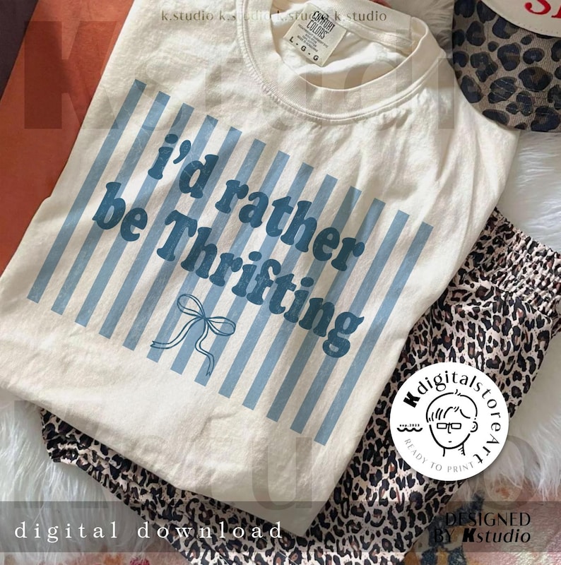 May include: Cream-colored t-shirt with the text "I'd rather be Thrifting" in blue, accented by blue vertical stripes and a bow graphic. Leopard print pants and a leopard print hat are also visible. The image also includes the text "digital download".