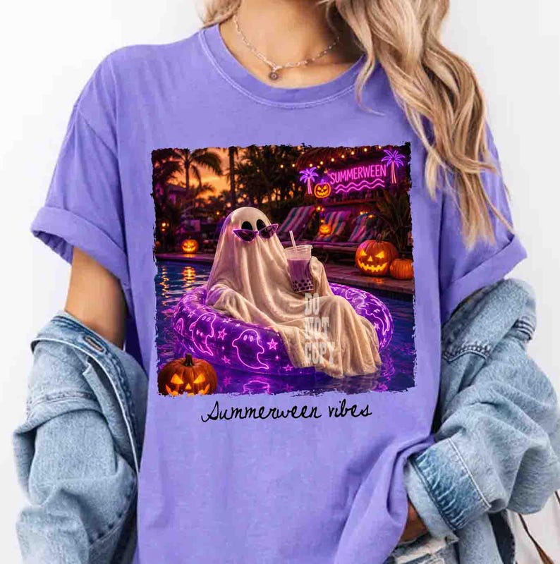 May include: A purple t-shirt with a graphic of a ghost wearing sunglasses, relaxing in a pool on a purple inflatable ring. The image includes jack-o'-lanterns and the text "Summerween vibes."