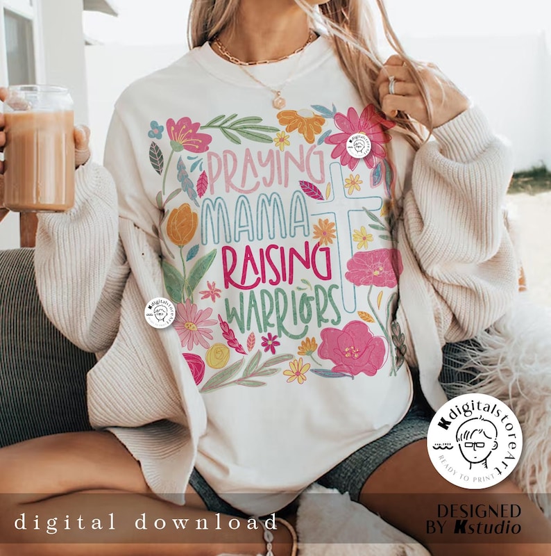 May include: White sweatshirt with a floral design and the text "Praying Mama Raising Warriors".