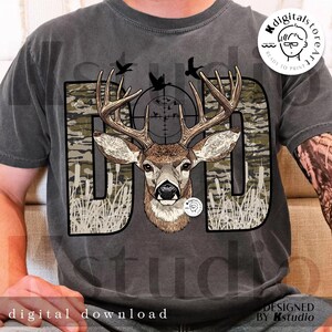 Op de afbeelding: Grijs t-shirt met een hertenafbeelding. Het woord "DAD" is ontworpen met een camouflagepatroon en een hertenkop in het midden. Het ontwerp bevat een vizier, vogels en de tekst "digital download".