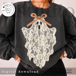 May include: A charcoal grey crewneck sweatshirt featuring a central graphic of a ghost shape composed of white floral lace. The ghost is adorned with a brown and white checkered ribbon bow at the top. The sweatshirt has a faded, vintage-style wash.