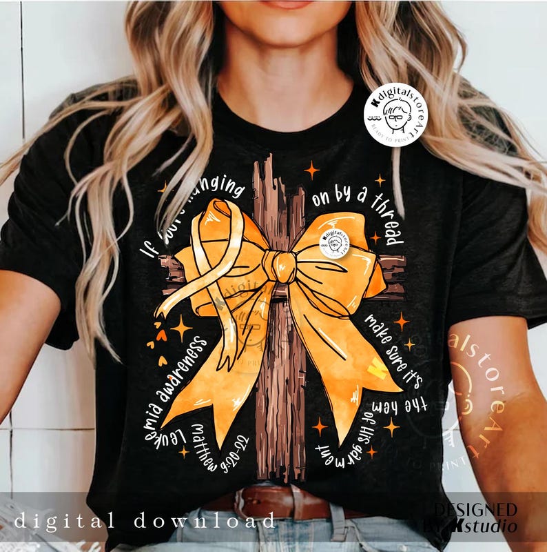 May include: A black t-shirt featuring a yellow ribbon tied in a bow on a brown cross. The text "If you're hanging on by a thread make sure it's the hem of His garment" is printed on the shirt. The text "Leukemia Awareness" is printed on the left side of the shirt. The text "Matthew 6:20-22" is printed on the bottom left side of the shirt.
