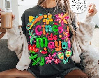 May include: A black t-shirt with a colorful graphic design featuring the text "Cinco de Mayo" surrounded by flowers, maracas, and chili peppers.