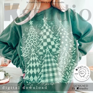 Puede incluir: Una sudadera de cuello redondo verde oscuro con un gran estampado gráfico blanco de cinco árboles de Navidad estilizados. Cada árbol muestra un patrón único que incluye estampado de leopardo, cuadros, lunares, rombos y enredaderas florales.