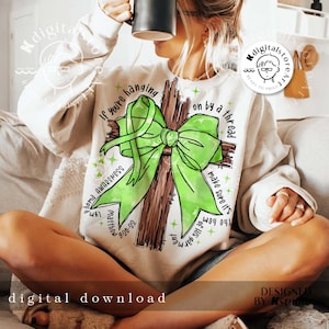May include: A white sweatshirt with a green ribbon tied around a brown cross. The text on the sweatshirt reads "If you're hanging on by a thread make sure it's the hem of His garment".  The text "Lyme Awareness" and "Matthew 9:20-22" are also on the sweatshirt.