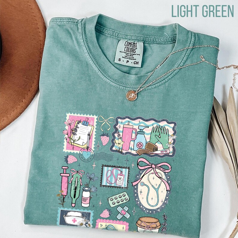 Op de afbeelding: Lichtgroen T-shirt met een kleurrijk medisch thema. De afbeelding bevat illustraties van medische instrumenten, zoals een stethoscoop, spuit en verband. De tekst "LIGHT GREEN" staat bovenaan.