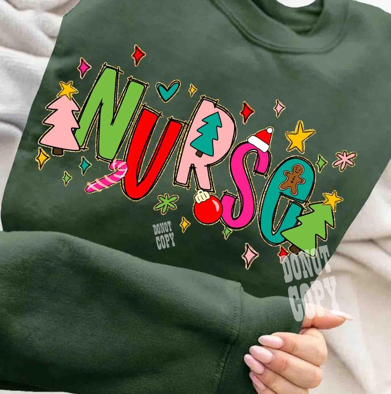 May include: Dark green sweatshirt with the word "NURSE" in colorful, festive lettering. The letters are decorated with Christmas-themed graphics, including a Christmas tree, gingerbread man, and candy cane. The words "Do Not Copy" are also visible.