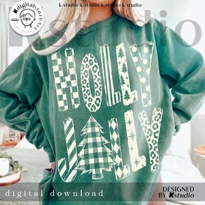 May include: A dark green crewneck sweatshirt featuring the text HOLLY JOLLY in large, cream-colored letters. Each letter displays a unique pattern, including checkered, leopard print, striped, polka dot, and Christmas tree motifs.