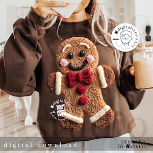 May include: A brown sweatshirt featuring a gingerbread man design. The gingerbread man has a smiling face, a red bow tie, and pink cheeks. The words "digital download" and "designed by Kstudio" are also visible.