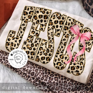 May include: A cream-coloured t-shirt featuring the word "JESUS" in a leopard print design, outlined in gold glitter. A pink bow is on the right side of the word. The words "digital download" are at the bottom.