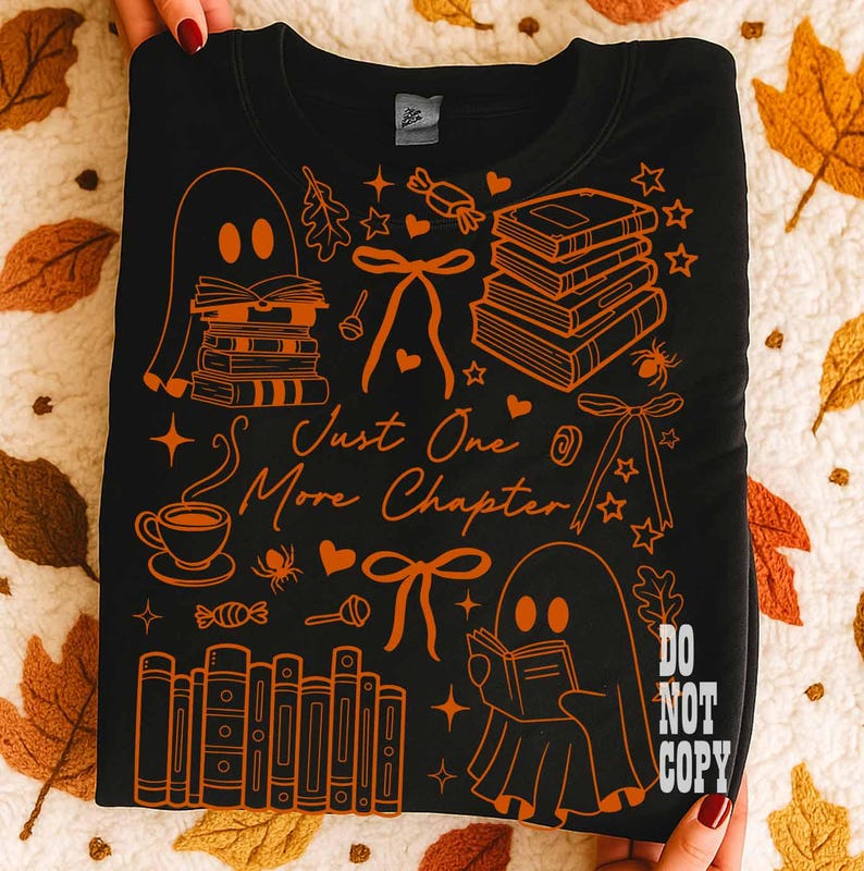 May include: Black sweatshirt with orange illustrations of books, ghosts, bows, and the text "Just One More Chapter." The design includes a coffee cup, stars, and the words "Do Not Copy."