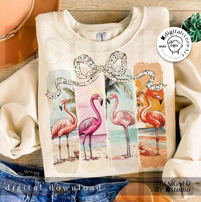 May include: Cream-colored sweatshirt featuring a colorful flamingo design. The graphic includes four flamingos on a beach, with a bow and the words "DIGITAL DOWNLOAD" at the bottom. The design is in a vintage style.
