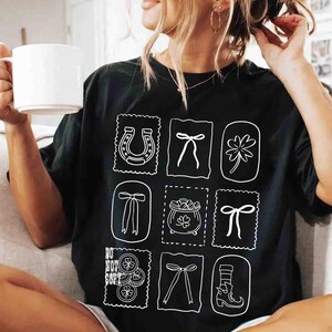 May include: Black t-shirt featuring a grid of white illustrations, including a horseshoe, bows, a four-leaf clover, and a pot of gold. The shirt also has the text "DO NOT COPY". The shirt is a casual style.