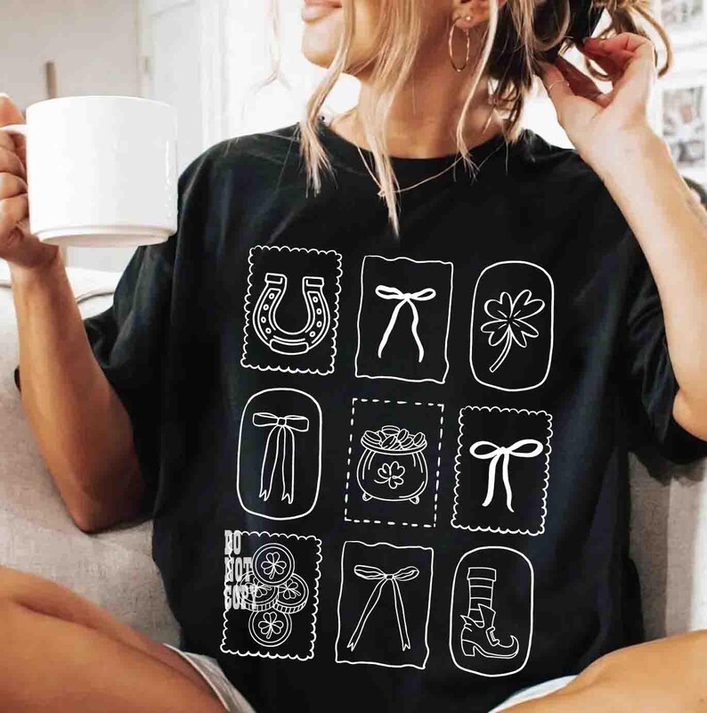 May include: Black t-shirt featuring a grid of white illustrations, including a horseshoe, bows, a four-leaf clover, and a pot of gold. The shirt also has the text "DO NOT COPY". The shirt is a casual style.