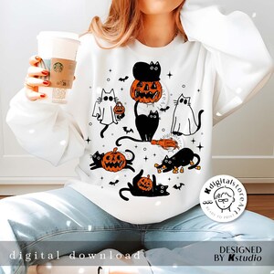 Puede incluir: Sudadera blanca con un dise&ntilde;o de Halloween con gatos negros, calabazas, murci&eacute;lagos y un fantasma. El dise&ntilde;o incluye el texto "digital download" y "DESIGNED BY Kstudio". La sudadera la lleva una persona.