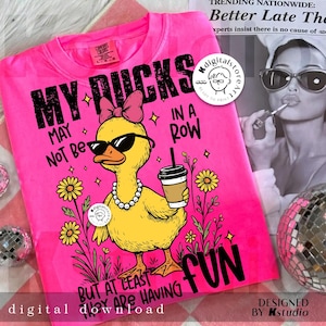 Puede incluir: Una camiseta rosa intenso con el texto "MY DUCKS MAY NOT BE IN A ROW BUT AT LEAST THEY ARE HAVING FUN." La imagen muestra un pato de dibujos animados con gafas de sol, un collar de perlas y una taza de caf&eacute;. El dise&ntilde;o incluye flores y estrellas.