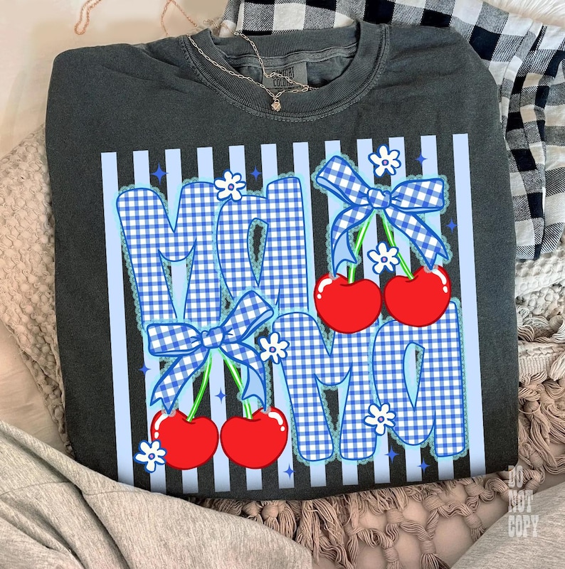 May include: Dark gray sweatshirt with a graphic design that says "MAMA" in blue gingham letters. The letters are decorated with blue bows, white flowers, and red cherries. The shirt has vertical light blue stripes.