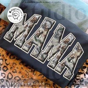 May include: A dark gray sweatshirt with the word "MAMA" in large, textured letters. The letters have a camouflage pattern and a cream-colored border. The image also includes the text "digital download" and a logo.
