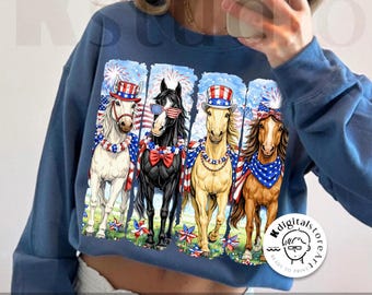 May include: Blue sweatshirt featuring a graphic of four horses adorned with patriotic accessories like hats, sunglasses, and scarves. The horses are set against a backdrop of fireworks and American flags. The words "digital download" are at the bottom.