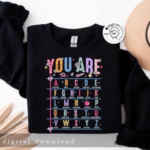 May include: Black sweatshirt with a colorful graphic that says "You Are" and lists positive adjectives for each letter of the alphabet.