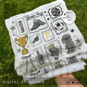 May include: White fabric featuring soccer-themed illustrations such as a trophy, football boots, a football, and the words "Game Day" and "Soccer." The design also includes stars, a whistle, and a foam finger. The text "Digital Download" is visible.
