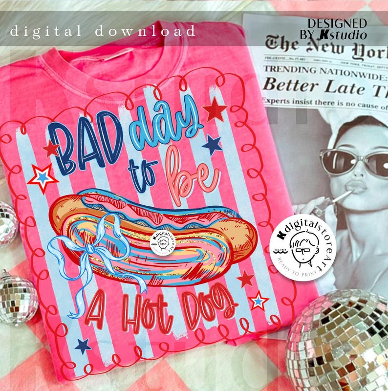 May include: Pink t-shirt with a graphic of a hot dog and the phrase "Bad Day to be a Hot Dog." The design includes blue and red stars and stripes. The words "digital download" are at the top.