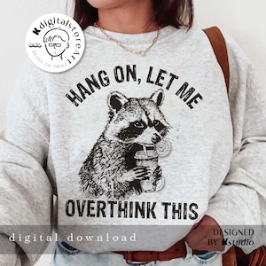 May include: A gray sweatshirt with a black and white illustration of a raccoon holding a cup with a straw. The text "HANG ON, LET ME OVERTHINK THIS" is printed on the sweatshirt.