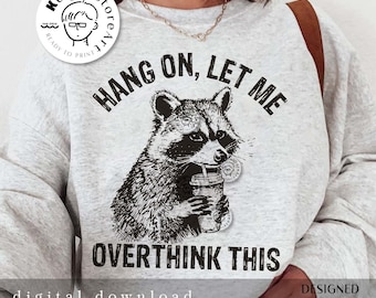 May include: A gray sweatshirt with a black and white illustration of a raccoon holding a cup with a straw. The text "HANG ON, LET ME OVERTHINK THIS" is printed on the sweatshirt.