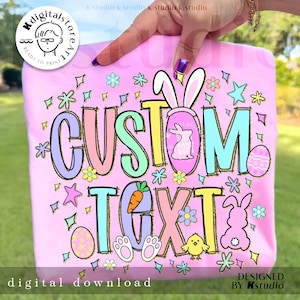May include: A pink t-shirt with the words "CUSTOM TEXT" in colorful bubble letters. The design includes Easter-themed graphics such as a bunny, eggs, flowers, and stars. The words "digital download" and "designed by Kstudio" are also visible.