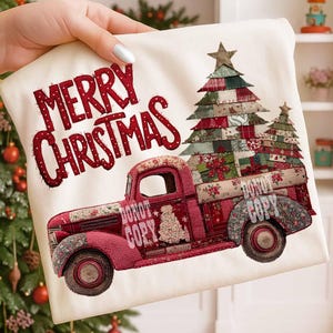 May include: A cream-colored Christmas-themed pillow with the words "MERRY CHRISTMAS" in red. The design features a red vintage truck carrying Christmas trees and gifts. The truck and trees are decorated with patchwork patterns.