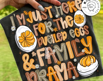 May include: Black t-shirt with the text "I'M JUST HERE FOR THE deviled eggs & FAMILY DRAMA" in various colors. The design includes illustrations of deviled eggs, daisies, and autumn leaves. "Digital download" is printed at the bottom.