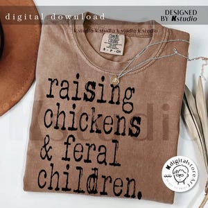 May include: A brown t-shirt with the text "raising chickens & feral children." printed in black.