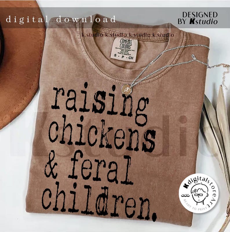 May include: A brown t-shirt with the text "raising chickens & feral children." printed in black.