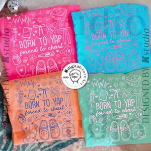 K&ouml;nnte beinhalten: Vier farbenfrohe T-Shirts mit dem Aufdruck "BORN TO YAP forced to chart" und medizinischen Grafiken. Die Shirts sind rosa, blau, orange und gr&uuml;n. Jedes Shirt hat ein einzigartiges Design mit Stethoskopen, Spritzen und anderen medizinischen Symbolen.