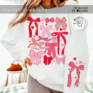 May include: A white sweatshirt with a design of pink and red bows and hearts. The text "digital download" and "DESIGNED BY Kstudio" is printed on the sweatshirt.