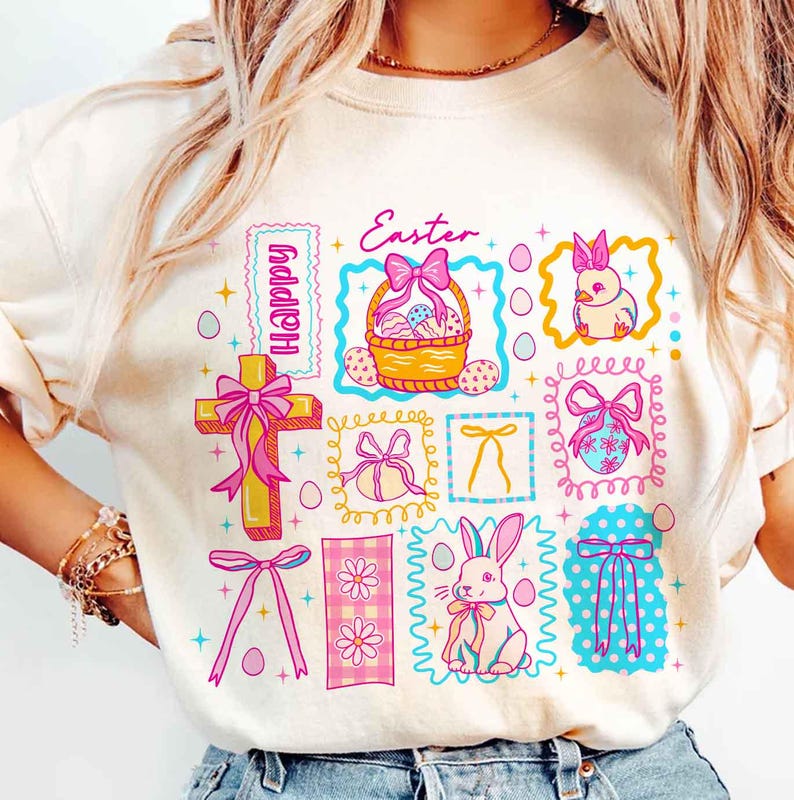 May include: Cream-colored sweatshirt featuring a colorful Easter-themed graphic. The design includes a cross, Easter basket, bunny, and eggs, with the words "Happy" and "Easter" in a playful font. The graphic is in shades of pink, yellow, and blue.