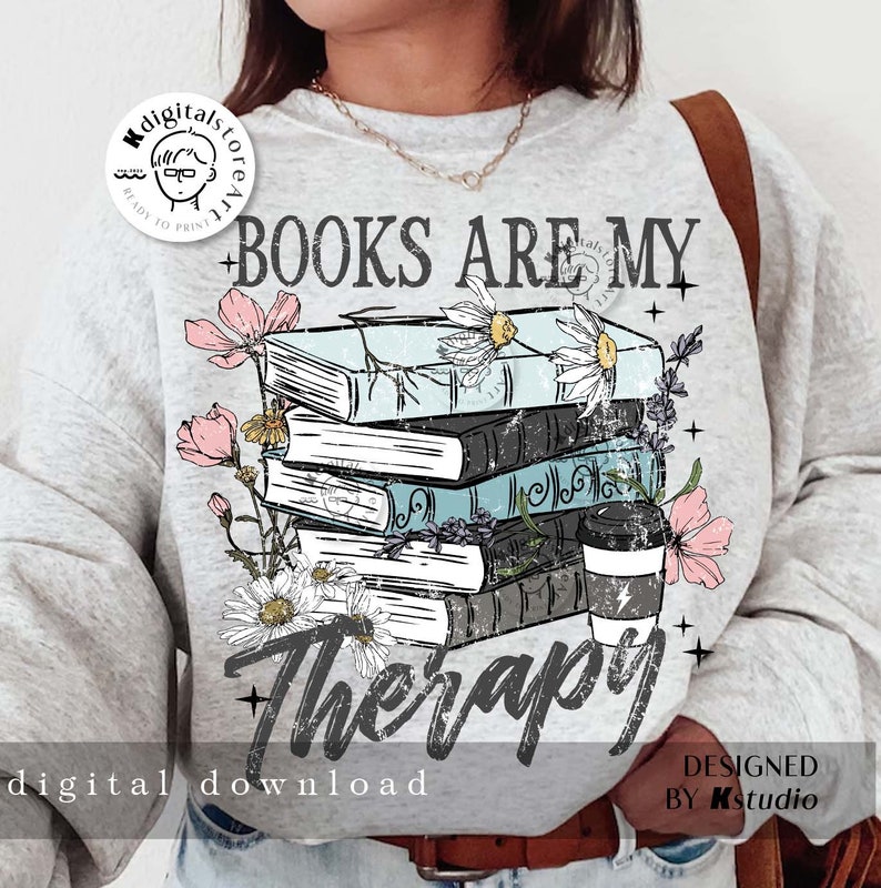 May include: A gray sweatshirt with a graphic design of a stack of books with flowers and a coffee cup. The text "BOOKS ARE MY THERAPY" is printed on the sweatshirt.
